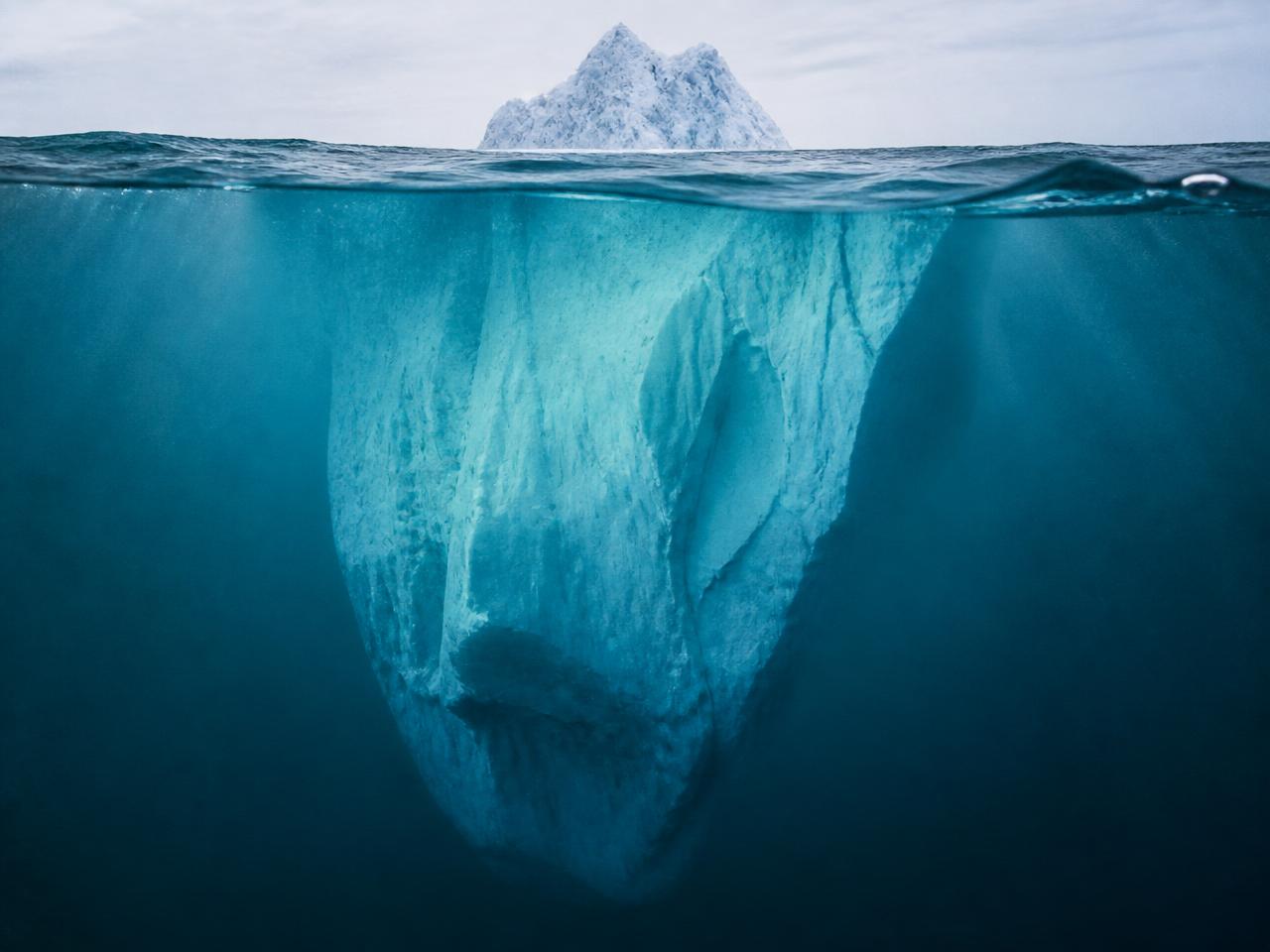 An iceberg with a small visible tip above the water and a vast hidden mass below — a metaphor for the subconscious mind.